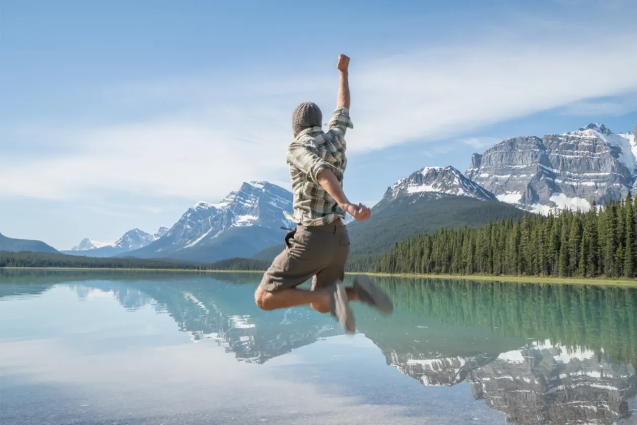 man jumping for joy mountain lake view